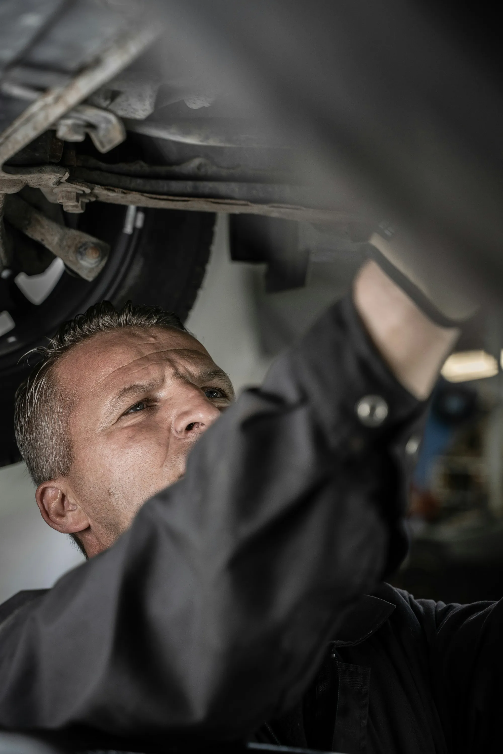Mechanic working beneath a raised vehicle with a work light
