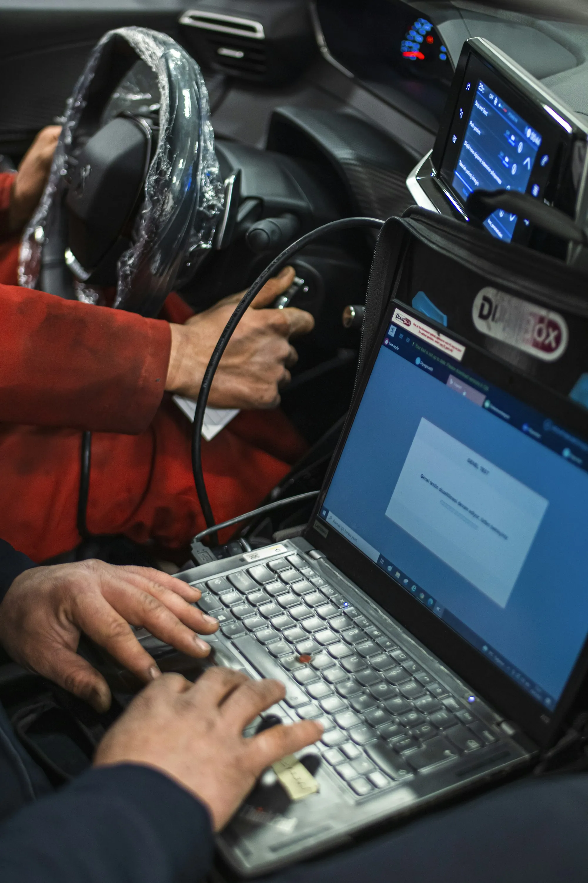 Technician typing on a laptop beside a steering wheel