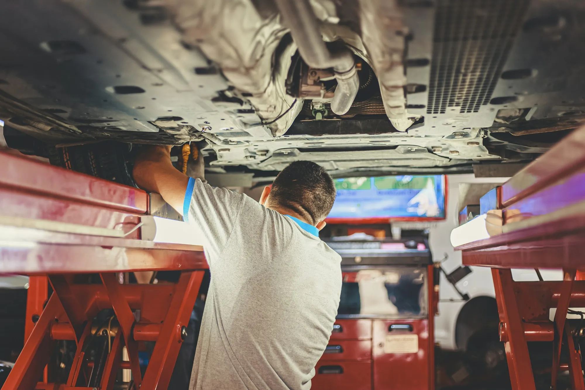 Technician working beneath a vehicle on a lift
